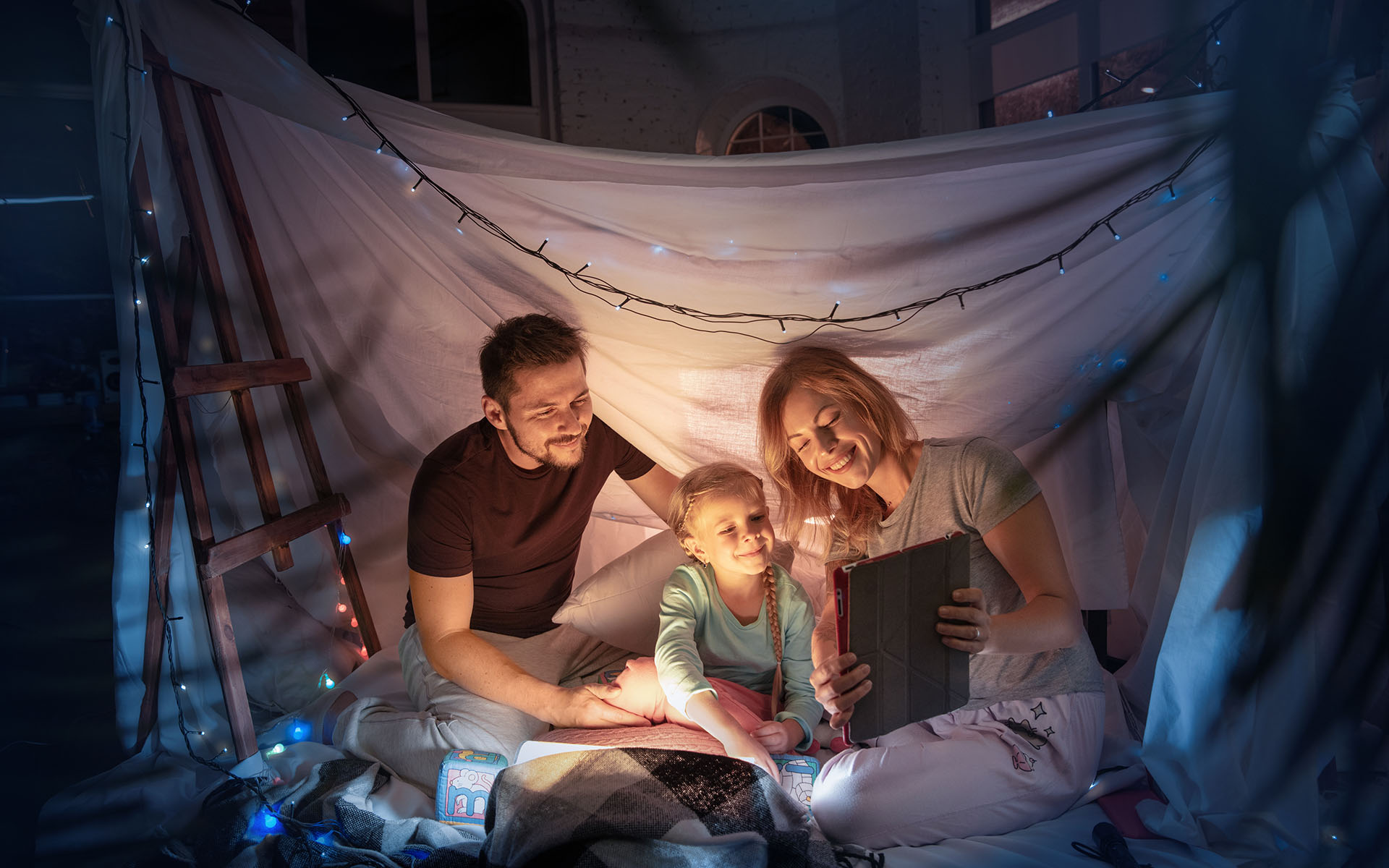 Family sitting in a teepee, having fun with the flashlight Family sitting in a teepee, having fun with the flashlight